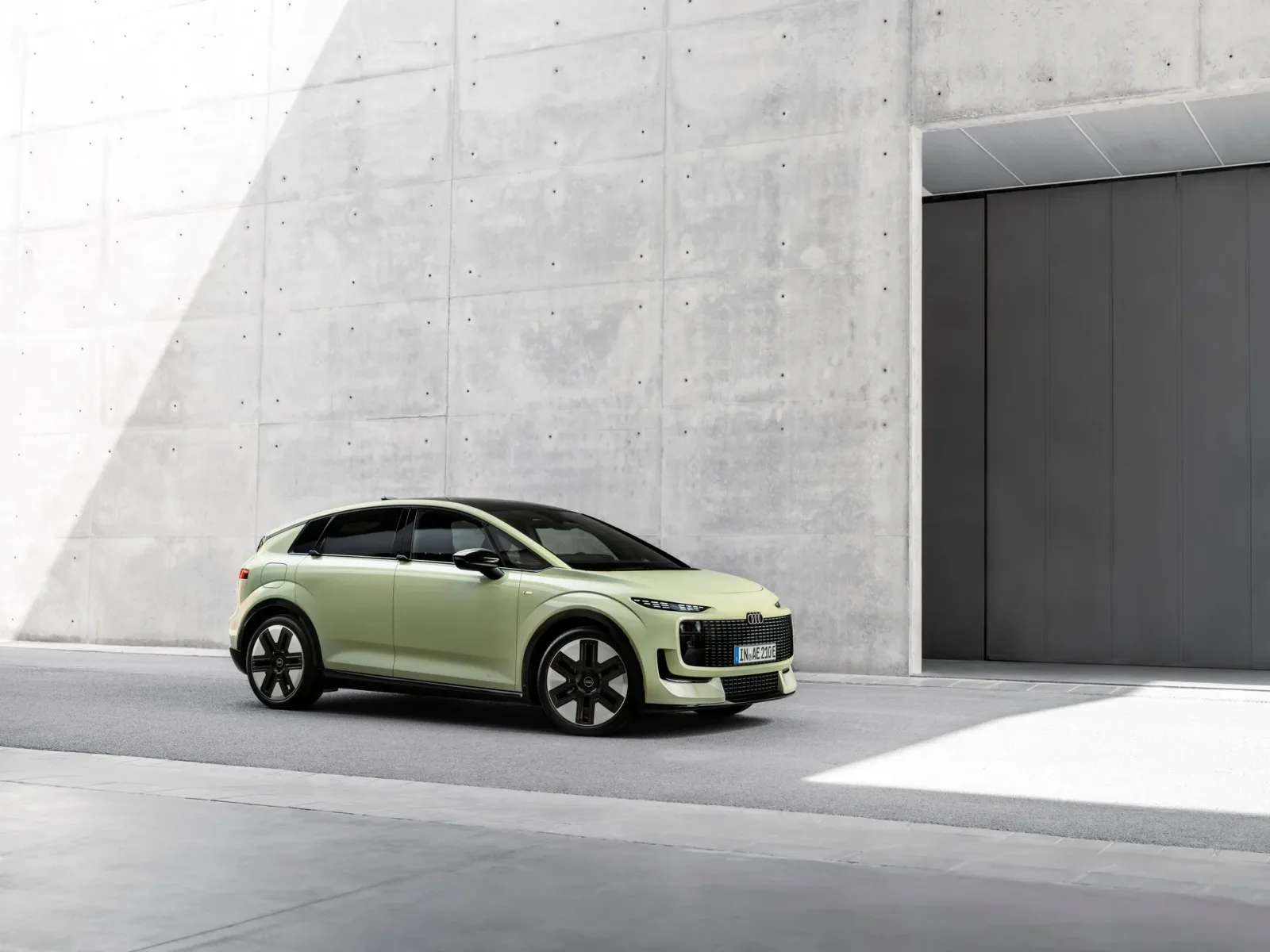 Pistachio green Audi A2 e-tron, front three-quarter view beside a building.