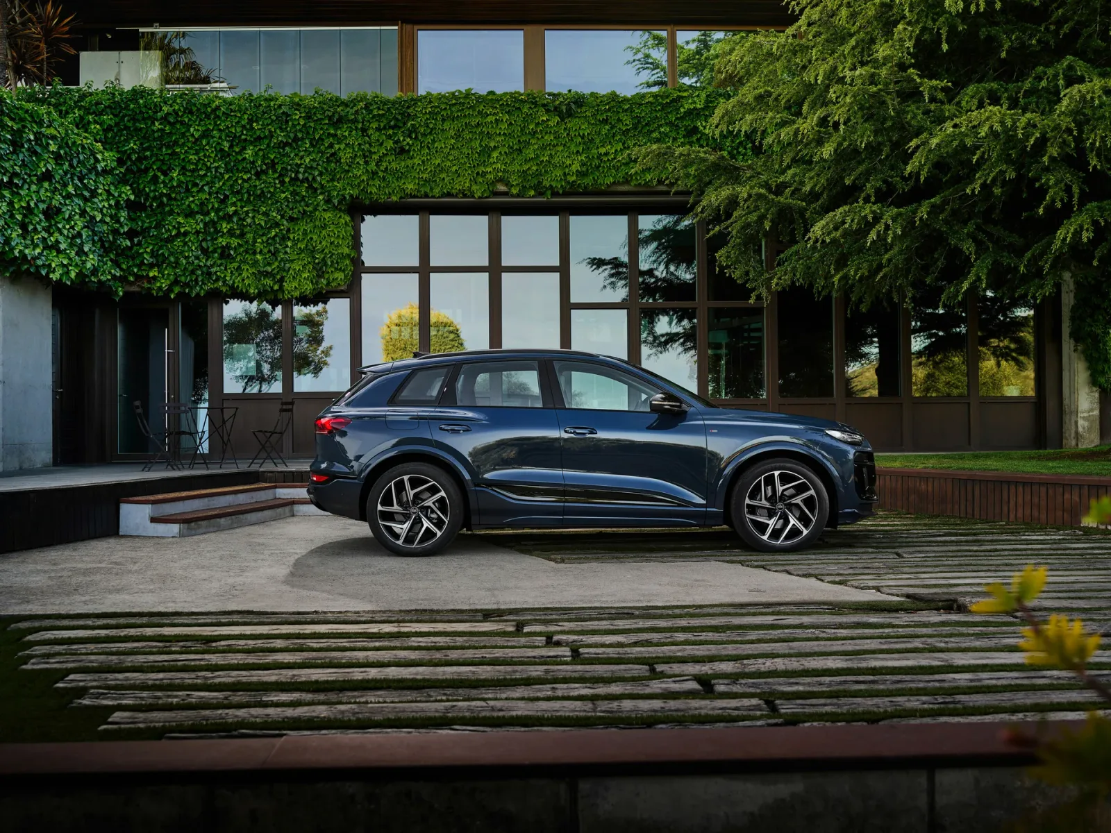 Blue Audi Q6 e-tron, side view beside a building.