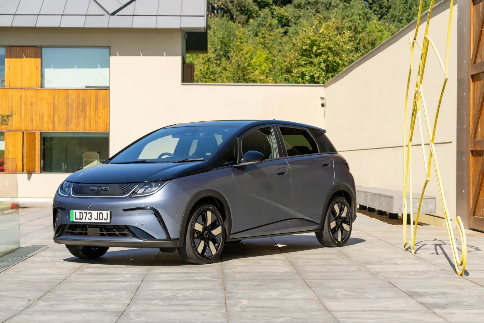 Grey BYD DOLPHIN, front three-quarter view beside a building.